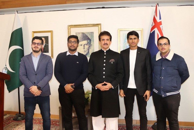 A group of men standing in front of a wall with flags

Description automatically generated