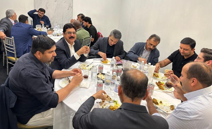 A group of men sitting at a table eating food

Description automatically generated