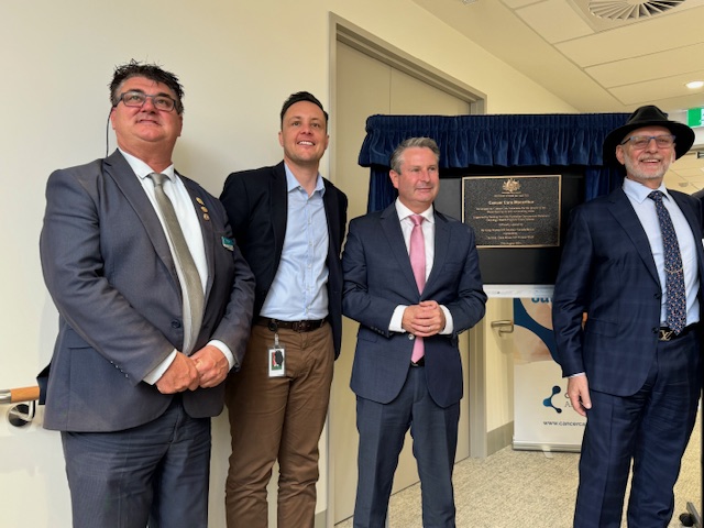 A group of men standing in front of a plaque

Description automatically generated