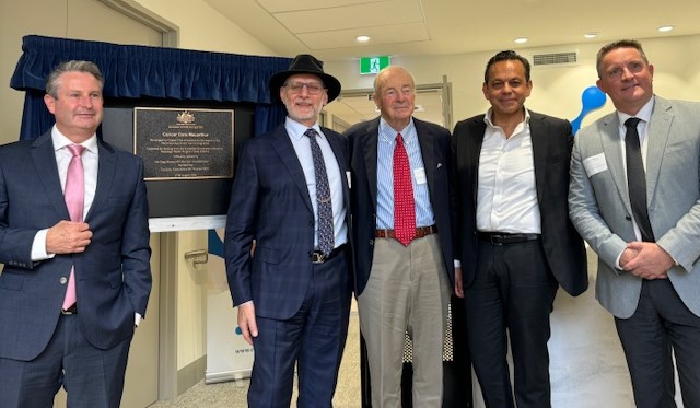 A group of men standing in front of a plaque

Description automatically generated