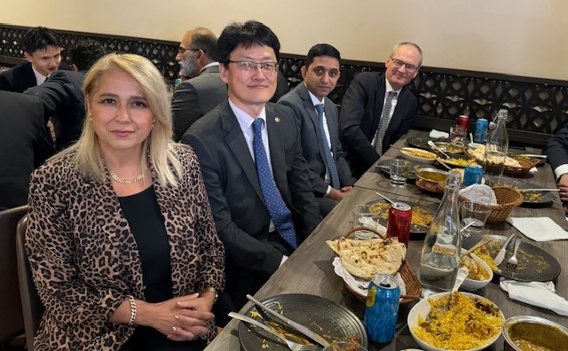 A group of people sitting at a long table with food

Description automatically generated