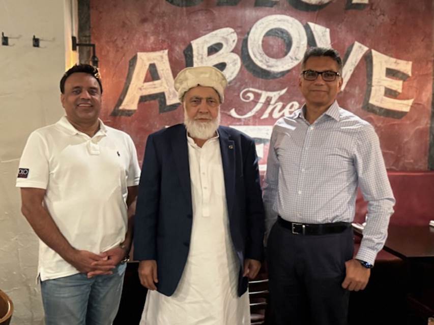 A group of men standing in front of a sign

Description automatically generated