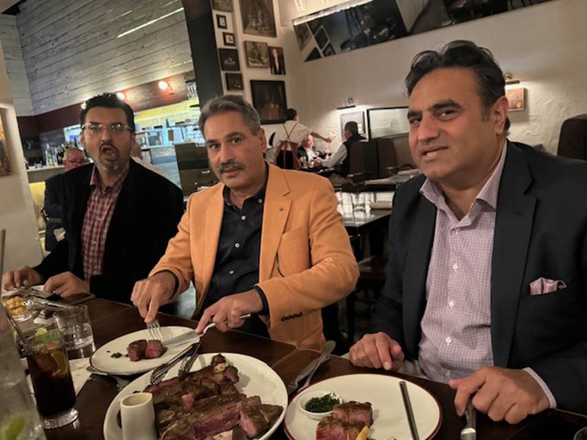 A group of men sitting at a table with plates of food

Description automatically generated