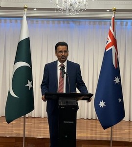 A person standing at a podium with flags behind him

Description automatically generated