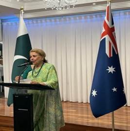 A person standing at a podium with flags behind her

Description automatically generated