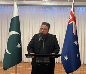 A person standing at a podium with a microphone and flags behind him

Description automatically generated