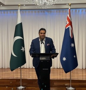 A person standing at a podium with flags behind him

Description automatically generated