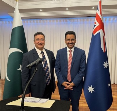 Two men standing in front of a microphone and flags

Description automatically generated