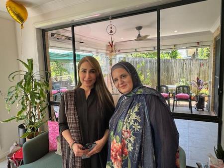 Two women standing in front of a glass door

Description automatically generated