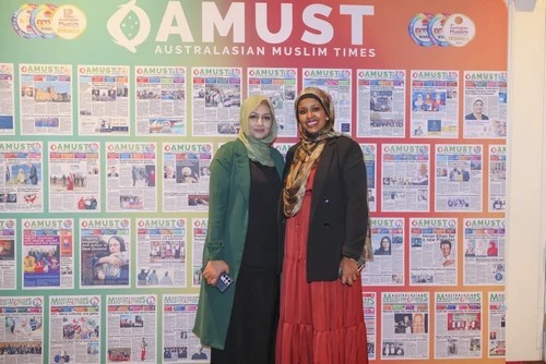 A couple of women standing in front of a wall of newspapers

Description automatically generated