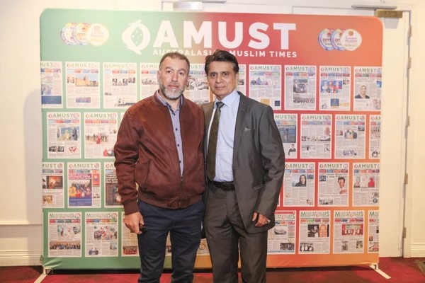 Men standing in front of a wall of newspapers

Description automatically generated