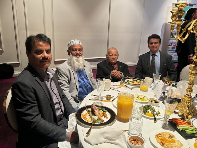 A group of men sitting at a table with food

Description automatically generated