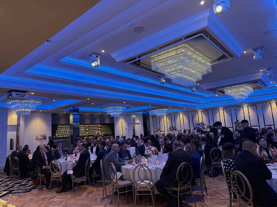 A group of people sitting at tables in a room with blue lights

Description automatically generated