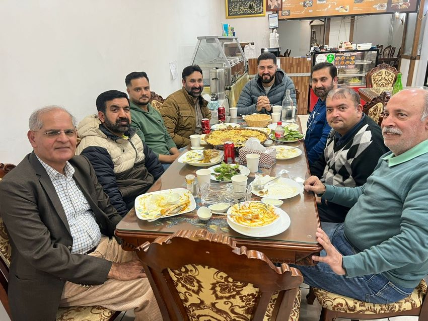 A group of men sitting at a table with food

Description automatically generated