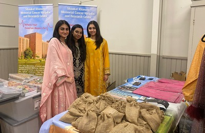 A group of women standing next to a table with burlap bags

Description automatically generated