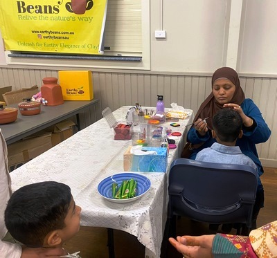 A person in a head scarf sitting at a table with children

Description automatically generated