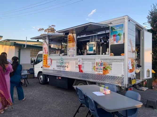 A food truck with tables and chairs

Description automatically generated