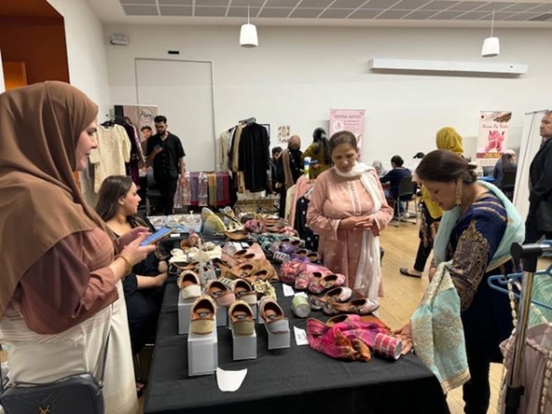 A group of women standing around a table with shoes

Description automatically generated