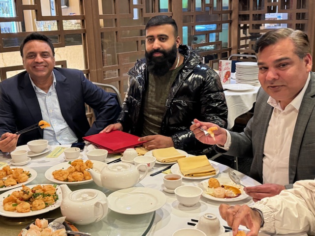 A group of men sitting at a table with food

Description automatically generated