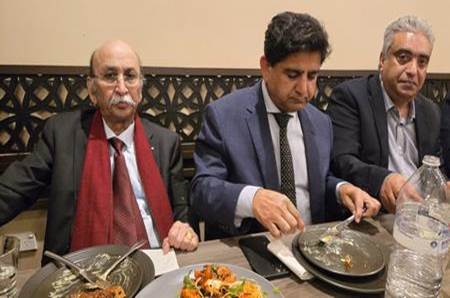 A group of men sitting at a table eating food

Description automatically generated