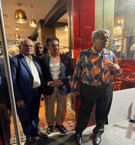 A group of men standing in front of a glass door

Description automatically generated