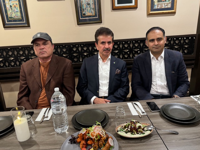 A group of men sitting at a table with plates of food

Description automatically generated