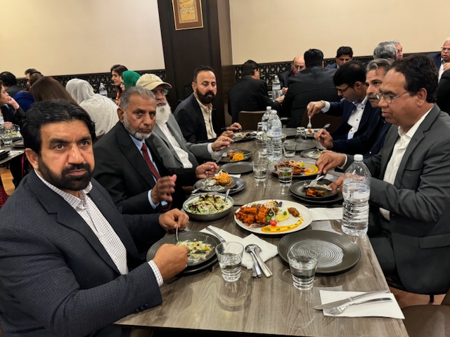 A group of men sitting at a table eating food

Description automatically generated