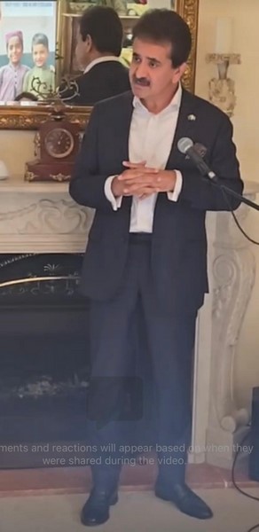 A person in a suit standing in front of a microphone

Description automatically generated