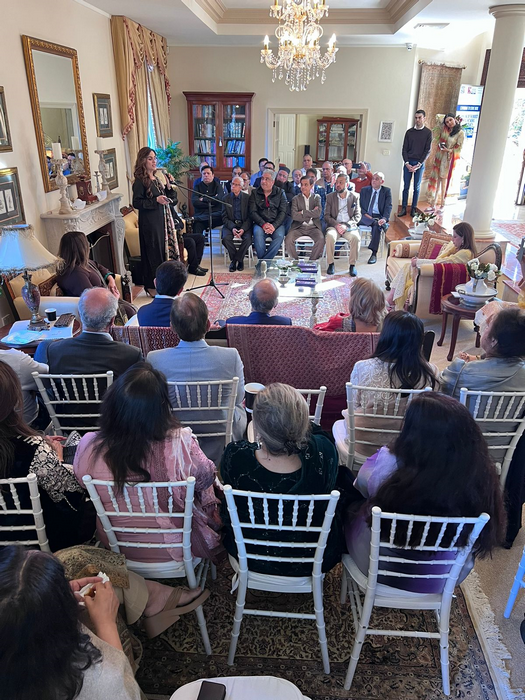 A group of people sitting in chairs in a room with a person playing a guitar

Description automatically generated