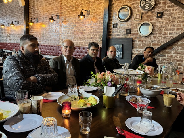 A group of men sitting at a table with food

Description automatically generated