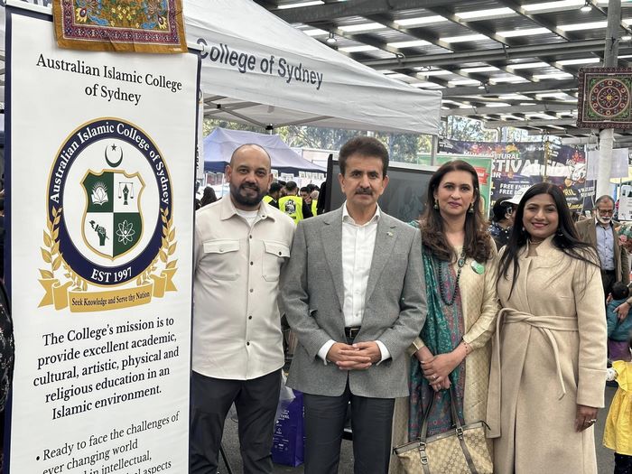 A group of people standing in front of a sign

Description automatically generated