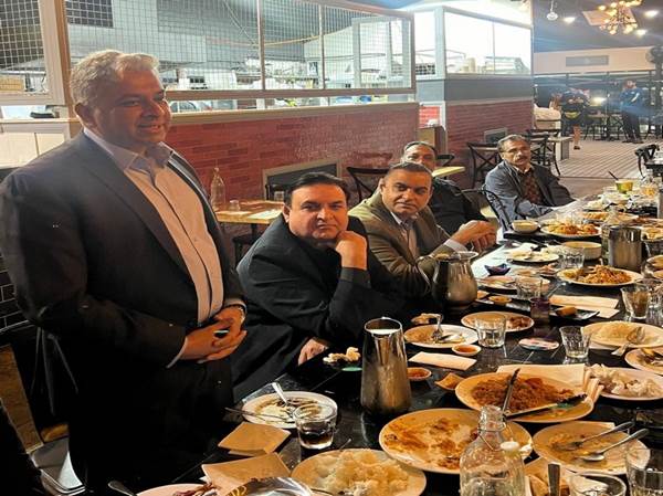 A group of men sitting at a table with food

Description automatically generated