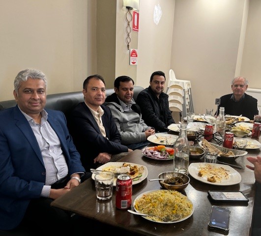 A group of men sitting at a table with food

Description automatically generated