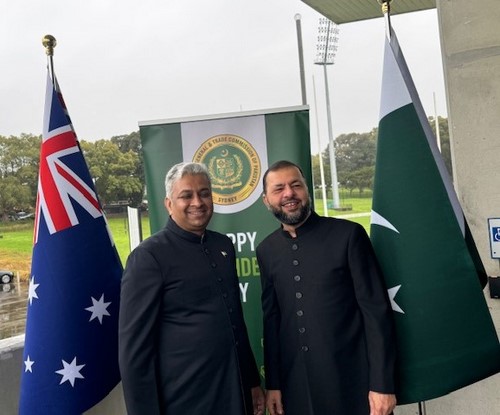 Two men standing in front of flags

Description automatically generated