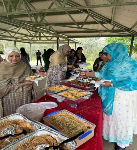 A group of women standing in front of a table full of food

Description automatically generated