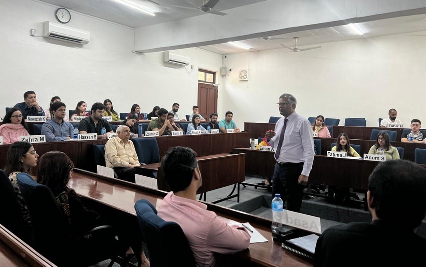 A person standing in front of a group of people in a lecture hall

Description automatically generated