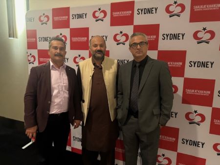 A group of men standing in front of a wall with red and white checkered walls

Description automatically generated