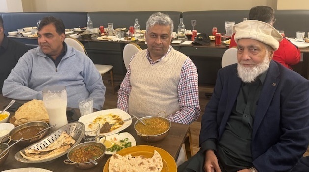 A group of men sitting at a table with food

Description automatically generated