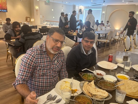 A group of men sitting at a table with food

Description automatically generated