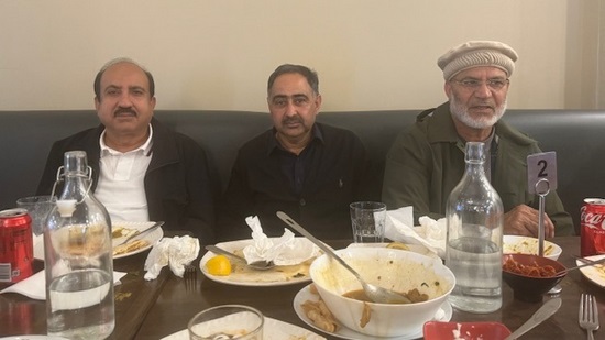 A group of men sitting at a table with food on plates

Description automatically generated