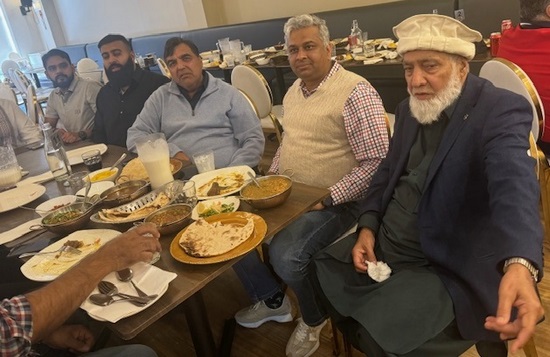 A group of men sitting at a table with food

Description automatically generated