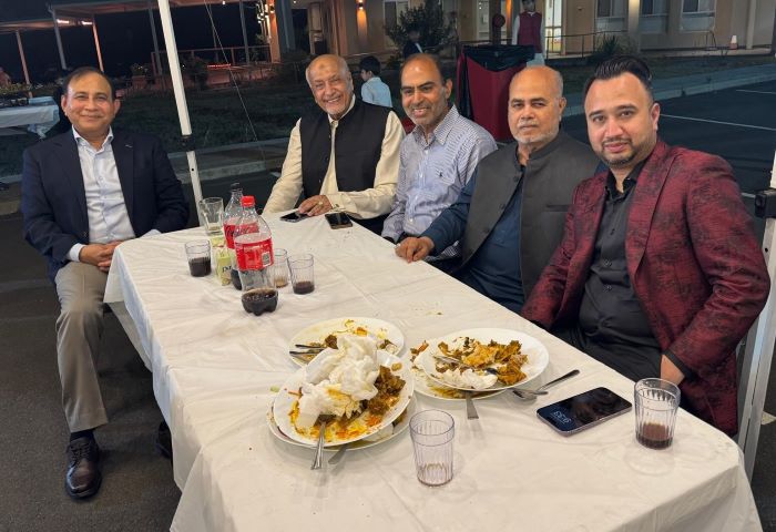 A group of men sitting at a table with plates of food

Description automatically generated