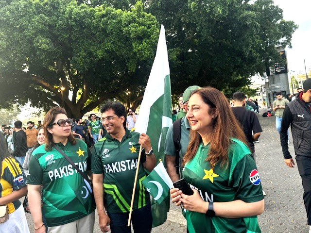 A group of people in green shirts holding a flag

Description automatically generated