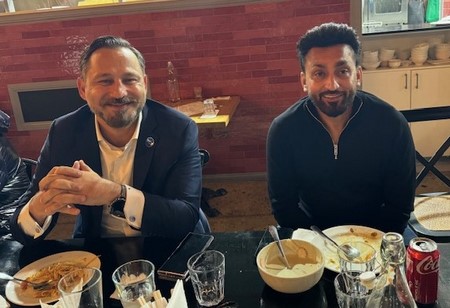 Two men sitting at a table with food

Description automatically generated