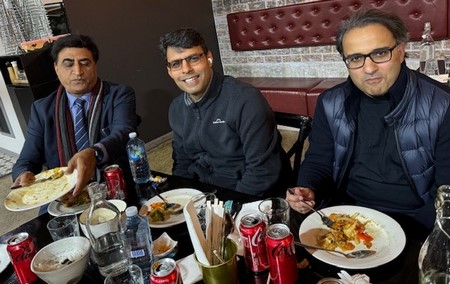 A group of men sitting at a table eating food

Description automatically generated