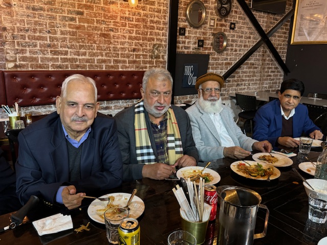 A group of men sitting at a table with plates of food

Description automatically generated