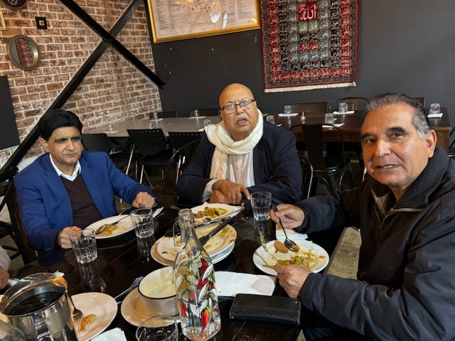 A group of men sitting at a table eating food

Description automatically generated