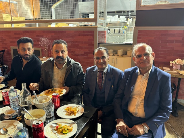 A group of men sitting at a table with food

Description automatically generated