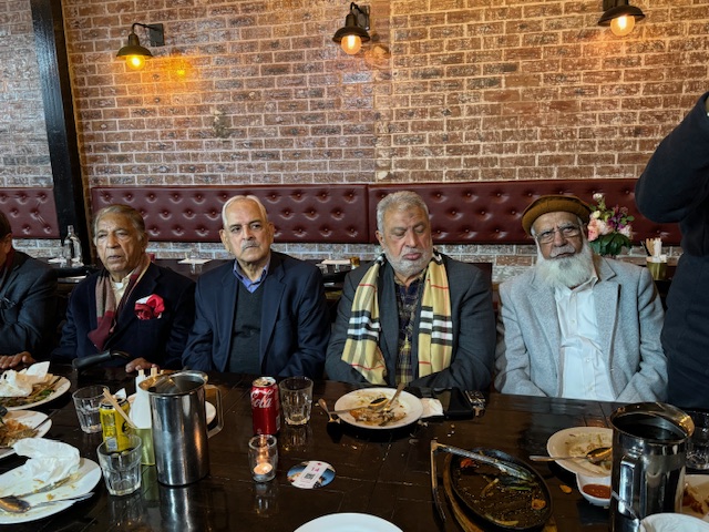 A group of men sitting at a table with food

Description automatically generated