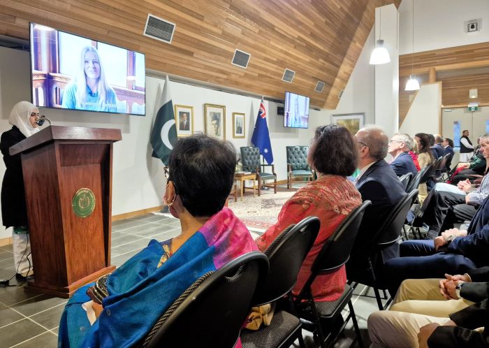 A group of people sitting in chairs watching a person on a television

Description automatically generated